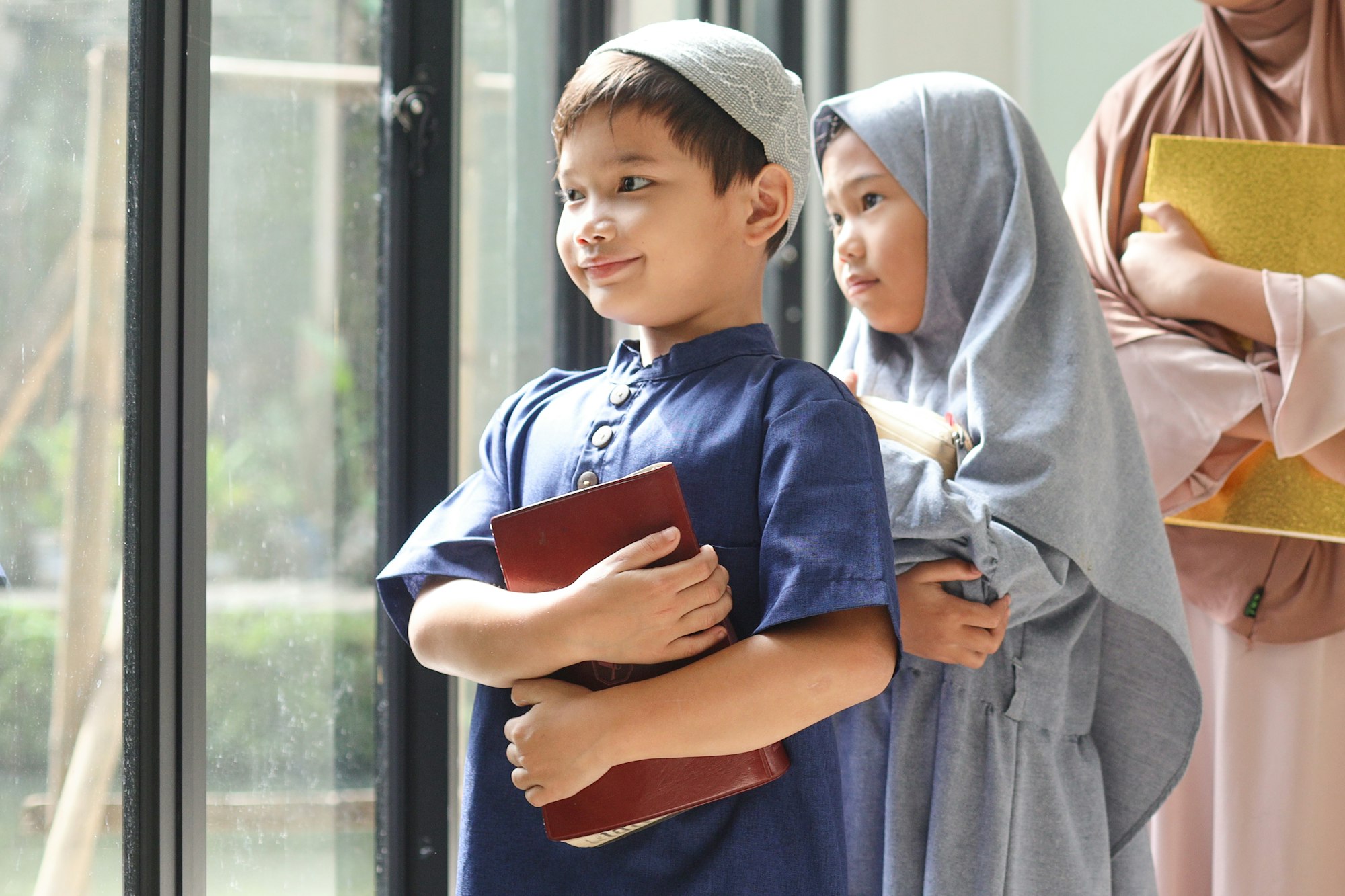 Adorable Muslim kids standing in a row and holding holy Quran